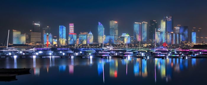 Illuminated modern buildings in city against sky at night