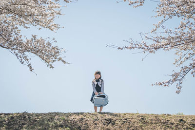 Low angle view of woman standing on field against sky