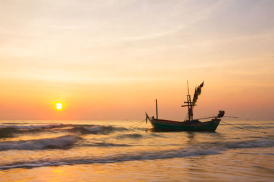 Silhouette of fishing boat at sunset over sea, fishing boat on the beach with sunset