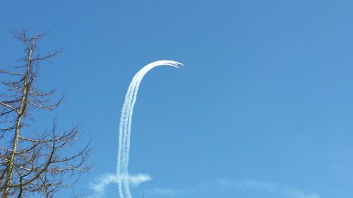 Low angle view of vapor trails against blue sky