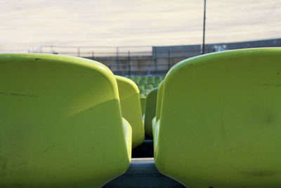 Empty yellow chairs at stadium during sunny day