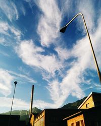 Low angle view of street light by factory against sky