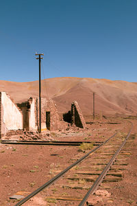 Railroad track in desert against clear blue sky