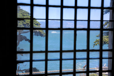 Sea seen through glass window against clear sky