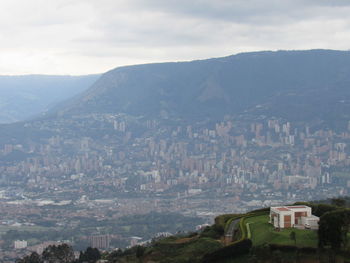 Aerial view of townscape by mountain against sky