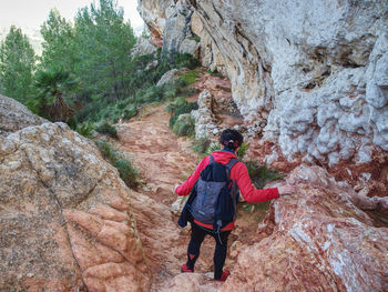 Rear view of man walking on rock against mountain