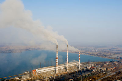 Smoke emitting from factory against sky