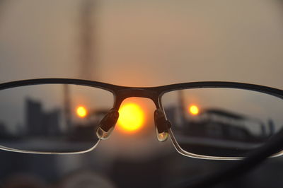 Close-up of sunglasses against sky during sunset