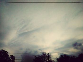 Low angle view of power lines against cloudy sky