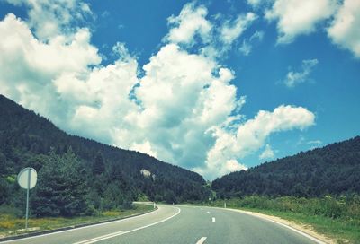 Road by mountains against sky