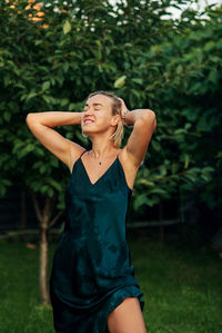 Portrait of young woman standing against plants