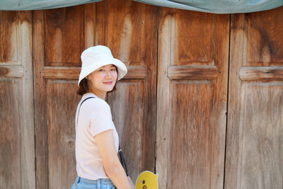 Portrait of young woman standing against door