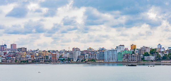 Buildings by sea against sky in city