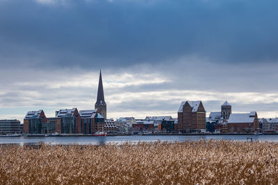 Buildings in city against cloudy sky