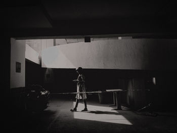 Rear view of man walking in illuminated tunnel