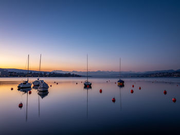 Sailboats moored in marina at sunset