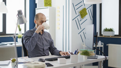 Side view of young woman using mobile phone in office