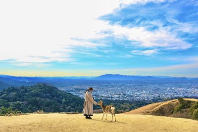 Rear view of woman walking on mountain against sky