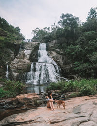 Woman standing on rock against waterfall