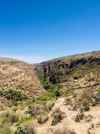 Scenic view of arid landscape against clear blue sky