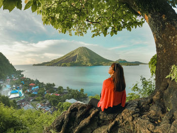 Rear view of woman standing on mountain against sky