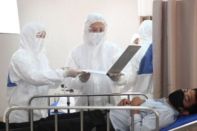 Doctors holding laptop by patient in hospital