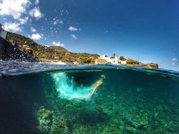 Man swimming undersea against blue sky