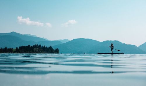 Man paddleboarding on lake against sky