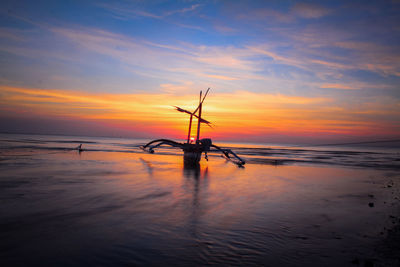 Silhouette poles on beach against sky during sunset