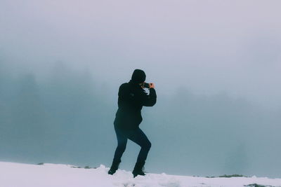 Full length of man standing on snow against sky