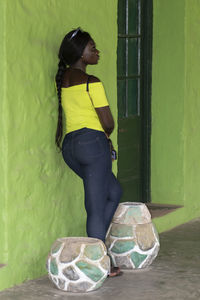 Side view of woman standing against wall