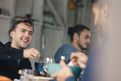 Happy young male friends sitting at dining table