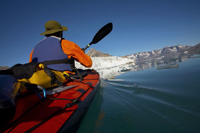 Man traveling on a sea-kayak though the fjords of eastern greenland