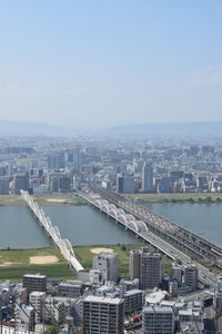 Aerial view of city by river and buildings against sky