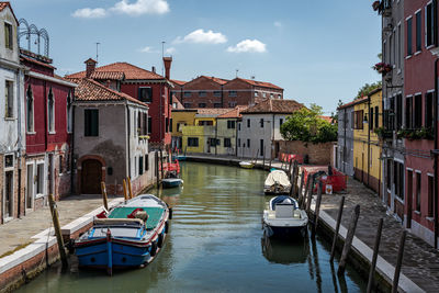 Boats moored in canal amidst buildings in city