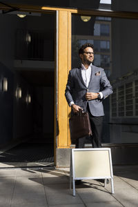 Male real estate agent standing with placard in front of apartment