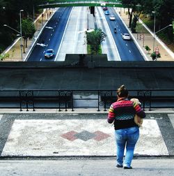 Rear view of woman standing on road in city