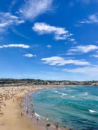 People enjoying at beach against blue sky