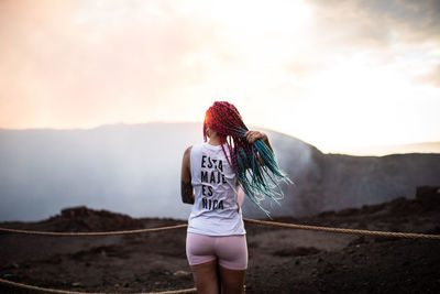 Rear view of woman standing on mountain against sky