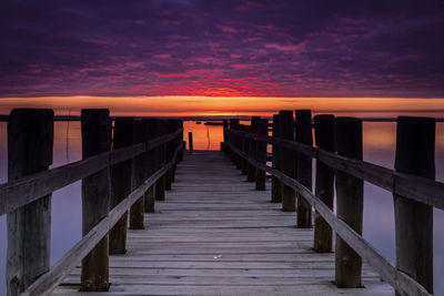 View of pier on sea against orange sky