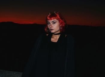 Portrait of redhead teenage girl standing against sky during dusk