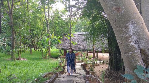 Rear view of women walking on footpath amidst trees