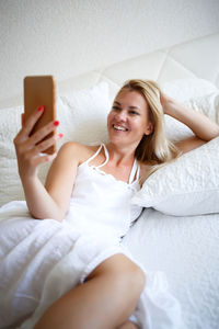 Young woman using mobile phone on bed at home