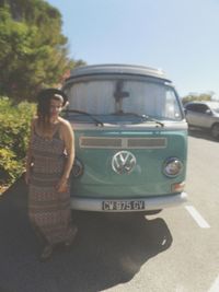 Young woman standing by car against clear sky