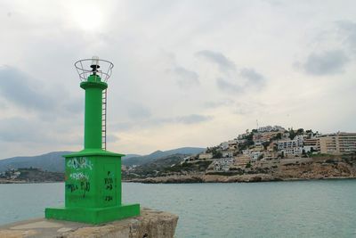 Lighthouse by sea against sky