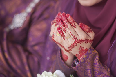 Midsection of bride praying with groom in background