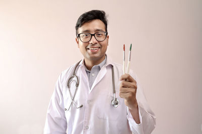 Portrait of smiling young man wearing eyeglasses against white background