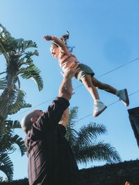 Low angle view of father playing  walking with his daughter against sky