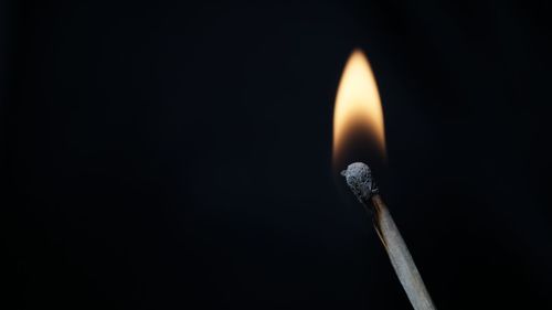 Close-up of illuminated matchstick against black background