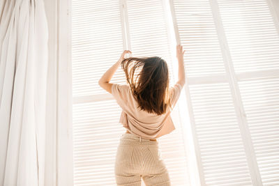 Rear view of woman standing against window